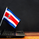 A Costa Rican flag standing behind a laptop.